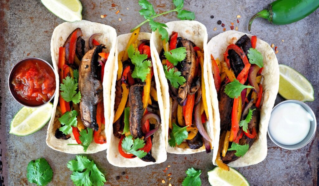 healthy, plant based meatless portobello mushroom steak fajitas, top view on a dark background